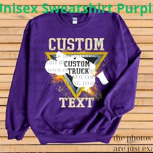 May include: A purple unisex sweatshirt with a custom design. The design includes the word "CUSTOM" above a yellow triangle with a truck graphic and the word "TEXT" below. The sweatshirt has the text "Unisex Sweatshirt Purple" at the top.