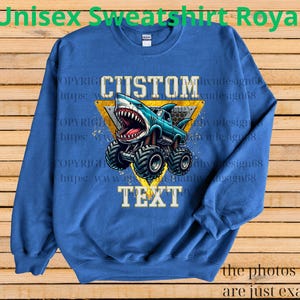 May include: Royal blue unisex sweatshirt featuring a monster truck with a shark design. The truck is blue with a shark head and large tires. The words "CUSTOM" and "TEXT" are displayed. The text "Unisex Sweatshirt Royal" is at the top.