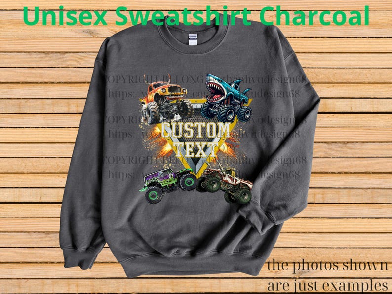 May include: Charcoal gray unisex sweatshirt featuring a graphic of four monster trucks with the text "CUSTOM TEXT" in a yellow and white design. The sweatshirt has the text "Unisex Sweatshirt Charcoal" at the top and "the photos shown are just examples" at the bottom.