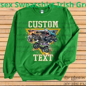 May include: Irish green unisex sweatshirt featuring a graphic of three monster trucks in orange, blue, and purple. The word "CUSTOM" is above the trucks, and "TEXT" is below. The sweatshirt is made of a soft material.
