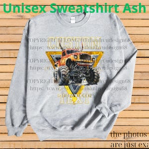 May include: Ash gray unisex sweatshirt featuring a monster truck graphic. The design includes a yellow triangle with the word "CUSTOM" and "TEXT" in a bold font. The sweatshirt has long sleeves and a crew neck.