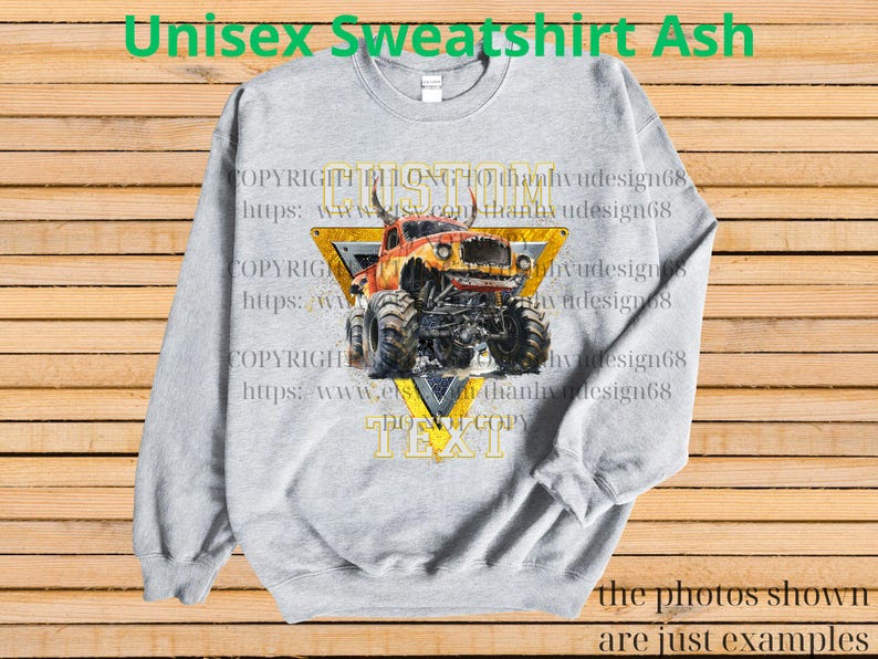 May include: Ash gray unisex sweatshirt featuring a monster truck graphic. The design includes a yellow triangle with the word "CUSTOM" and "TEXT" in a bold font. The sweatshirt has long sleeves and a crew neck.
