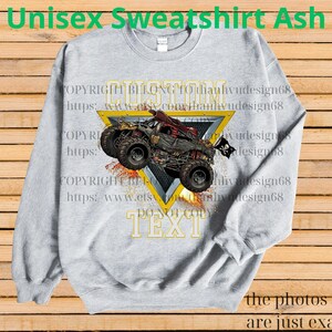May include: Ash gray unisex sweatshirt featuring a monster truck design within a yellow triangle. The truck is red and black with large tires. The text "CUSTOM TEXT" is below the truck. The words "Unisex Sweatshirt Ash" are at the top.