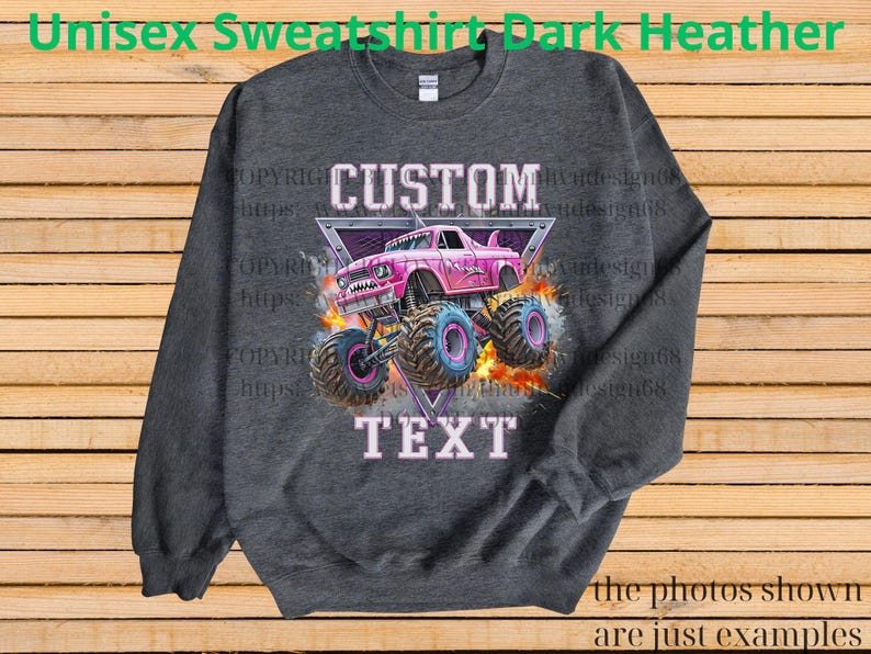 Op de afbeelding: Donkergrijs unisex sweatshirt met een roze monster truck afbeelding. De afbeelding bevat de woorden "CUSTOM" en "TEXT" in een lichtroze lettertype, met een driehoekige achtergrond.