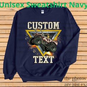May include: Navy blue unisex sweatshirt with a custom design. The design features a monster truck inside a yellow triangle, with the words "CUSTOM" and "TEXT" in white. The sweatshirt has long sleeves and a crew neck.