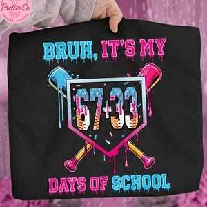 Pode incluir: Camiseta preta com o texto "BRUH, IT'S MY DAYS OF SCHOOL" em azul e rosa. O design inclui um diamante de beisebol com os n&uacute;meros "67+33" e bast&otilde;es de beisebol cruzados.