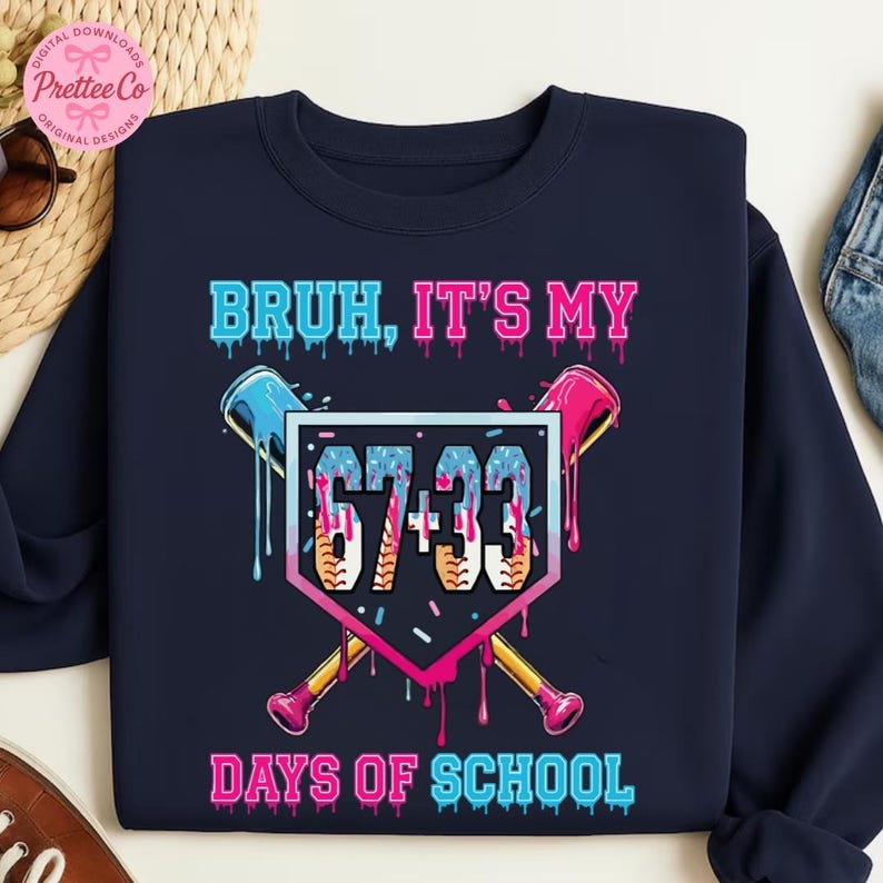 Pode incluir: Camisola azul marinho com um gr&aacute;fico com tema de beisebol. O design apresenta o texto "BRUH, IT'S MY 67+33 DAYS OF SCHOOL" em fonte rosa e azul gotejante, com bast&otilde;es de beisebol cruzados e uma base de beisebol.