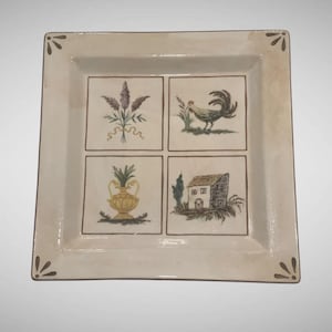 May include: Square ceramic serving platter with a cream-colored background and four square illustrations. The illustrations depict lavender, a rooster, a vase, and a house. Brown accents frame the illustrations and decorate the corners.