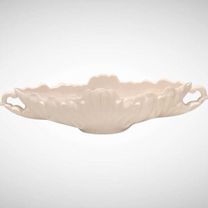 May include: A cream-colored, ceramic serving bowl with a scalloped rim and two ornate handles. The bowl has a petal-like design and is ideal for serving salads or displaying decorative items. The bowl is approximately 14 inches long.