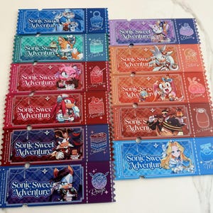 May include: A collection of twelve rectangular paper tickets featuring Sonic Sweet Adventure branding. Each ticket displays a unique character illustration, a dessert icon, and the text Sonic Sweet Adventure in a stylized white script font.