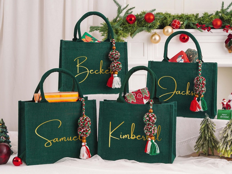 May include: Four green tote bags with gold script names: Beckett, Samuel, Jacks, and Kimberly. Each bag has a matching handle and a decorative tassel with red, white, and green accents. The bags are filled with gifts and are set against a festive holiday backdrop.