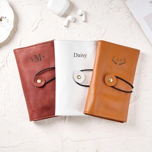 以下が含まれることがあります： 赤、白、茶色の3つの革製ジャーナル。それぞれユニークなデザインです。赤いジャーナルには「LMs」のイニシャル、白いジャーナルには「Daisy」という名前、茶色のジャーナルには鹿の角のデザインが施されています。各ジャーナルにはボタン留めが付いています。