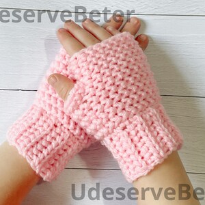 May include: A pair of light pink, handmade crochet fingerless gloves. The gloves are made of a soft yarn and feature a ribbed cuff. The text "UdeserveBeter" is visible in the image.