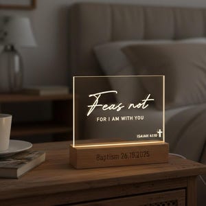 May include: A rectangular LED night light with the words "Fear not, for I am with you" and "Isaiah 41:10" printed on the front. The light sits on a wooden base with the date "Baptism 26.10.2025" engraved. The light is on a wooden nightstand.