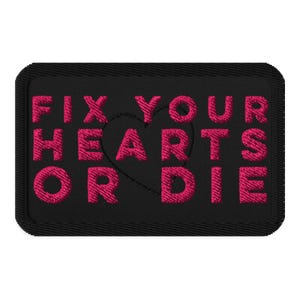 Puede incluir: Parche bordado negro con el texto "FIX YOUR HEARTS OR DIE" en rosa brillante. Un corazón está en el centro del texto. El parche tiene forma rectangular con esquinas redondeadas. El texto y el corazón están bordados.