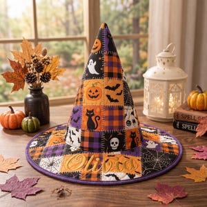 May include: A conical witch hat featuring a patchwork design of orange, black, and purple squares with Halloween motifs including pumpkins, ghosts, black cats, skulls, bats, and spiderwebs. The brim is embroidered with the name Olivia in script.