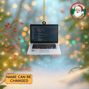 May include: A silver laptop Christmas ornament with a black keyboard and screen displaying code. The ornament hangs from a gold chain. A Santa Approved seal is in the upper right corner, and the text "NAME CAN BE CHANGED" is at the bottom.