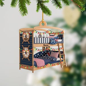 May include: Wooden bunk bed Christmas ornament with nautical theme. Features a navy blue and wood design with ship wheels, sailboats, and star-patterned bedding. Includes a ladder and string lights. The word "Name" is visible.