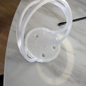 Peut inclure: Un support mural en plastique blanc pour bouteille d'eau. Le support a une base circulaire avec quatre trous pour le montage.