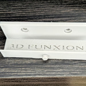 May include: White plastic wall mount with two holes for screws and the text "3D FUNXION" printed on the front.