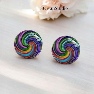 Peut inclure: Une paire de boucles d'oreilles clous en forme de spirale colorée. Les boucles d'oreilles sont rondes et ont un dos argenté. Le motif en spirale est composé de plusieurs couleurs, dont le violet, le vert, le bleu, le jaune, l'orange et le rouge.
