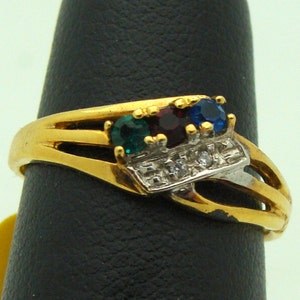 May include: Gold ring with a row of small clear stones and three larger stones: green, red, and blue.