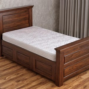 May include: A wooden bed frame with a headboard and footboard. The bed frame is made of dark brown wood and has a white mattress. The bed frame is on a hardwood floor.