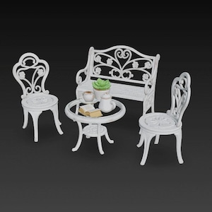 Puede incluir: Un juego de patio blanco en miniatura con un banco, dos sillas y una mesa redonda. La mesa tiene un libro pequeño, tazas de té, una tetera y una planta suculenta. El conjunto tiene detalles ornamentados y decorativos.