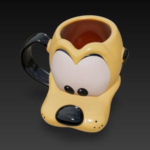 Puede incluir: Una taza de cerámica amarilla con forma de la cara de Pluto, con un asa y detalles en negro. La taza presenta los ojos blancos, la nariz negra y las orejas negras de Pluto. El interior de la taza es marrón.