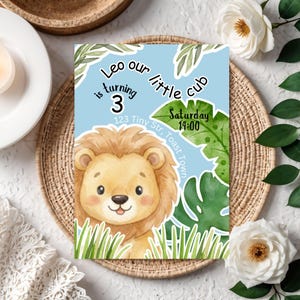 Pode incluir: Convite de aniversário azul com uma ilustração de leão de desenho animado. O texto diz "Leo faz 3 anos" com a data e a hora. O design inclui folhas verdes e grama.