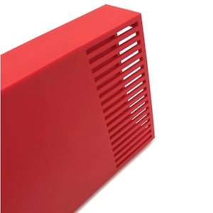 Peut inclure: Un objet rectangulaire rouge vif avec une s&eacute;rie de fentes parall&egrave;les et inclin&eacute;es sur un c&ocirc;t&eacute;. L'objet a une finition lisse et mate et est pos&eacute; sur un fond blanc. Le design sugg&egrave;re une esth&eacute;tique moderne et minimaliste.