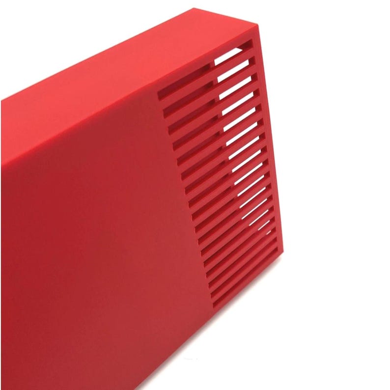 Peut inclure: Un objet rectangulaire rouge vif avec une s&eacute;rie de fentes parall&egrave;les et inclin&eacute;es sur un c&ocirc;t&eacute;. L'objet a une finition lisse et mate et est pos&eacute; sur un fond blanc. Le design sugg&egrave;re une esth&eacute;tique moderne et minimaliste.