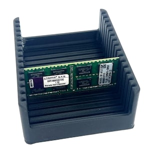 May include: A black, ribbed plastic storage container holding a green and black Kingston KVR memory module. The module has text that reads "KVR1066D3S7/2G 1.5V Warranty Void If Removed".