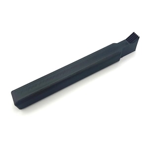 May include: A black, rectangular tool with a textured handle and a brush-like end. The tool is angled and appears to be made of plastic. The brush end has several small, black bristles.