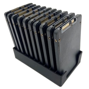 Può includere: Un rack di archiviazione SSD nero che contiene più unità a stato solido nere. Le unità sono disposte in una fila verticale, con connettori dorati visibili. Il rack è realizzato in plastica nera e si trova su uno sfondo bianco.