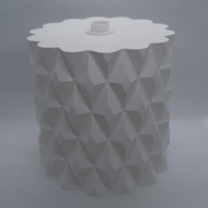 May include: A white, geometric-patterned container with a lid. The container has a cylindrical body with a repeating diamond pattern. The lid is scalloped and has a small, circular handle. The overall design is modern and minimalist.