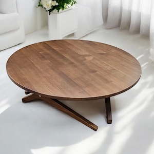 May include: A round, low wooden coffee table with a dark brown finish. The table has a simple design with a solid wood top and angled legs. The table is approximately 91 cm in diameter.