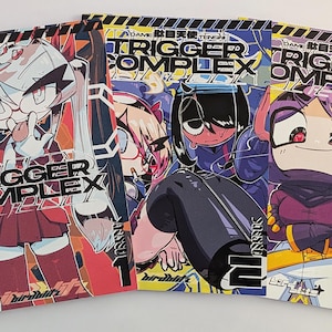 Peut inclure: Trois mangas intitulés "TRIGGER COMPLEX" avec des illustrations de style anime. Chaque couverture présente un personnage différent avec des couleurs vives et une typographie audacieuse. Les livres sont numérotés 1, 2 et 3. L'ensemble dégage une esthétique manga.