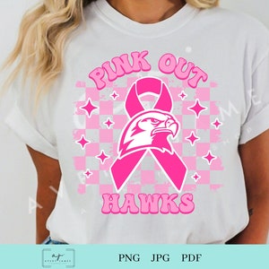 Op de afbeelding: Pink Out Hawks T-shirt ontwerp met een roze lint en een witte adelaar mascotte. Het ontwerp heeft een geruite achtergrond met roze sterren.