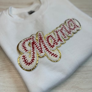 May include: White sweatshirt with a red and gold baseball-themed applique that says "Mama".