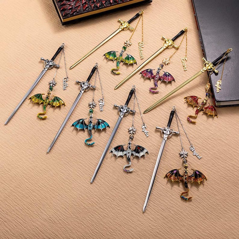 May include: Collection of sword-shaped bookmarks with dragon pendants. The bookmarks feature silver and gold tones, with colorful dragon designs in green, blue, red, and white. Each bookmark has a chain with a name tag.