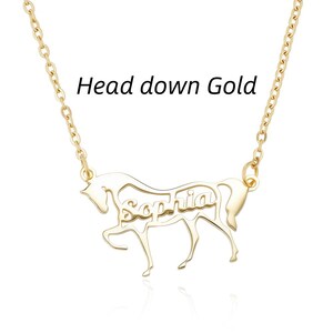 May include: A gold-toned necklace featuring a pendant shaped like a horse with its head down. The name Sophia is cut out from the center of the horse's body. The text Head down Gold is visible above the pendant, which hangs from a delicate chain.