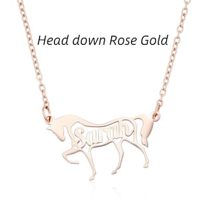 May include: A rose gold necklace featuring a pendant shaped like a horse with its head down. The name Sarah is cut out from the center of the horse's body. The text Head down Rose Gold is visible above the pendant on the plain white background.