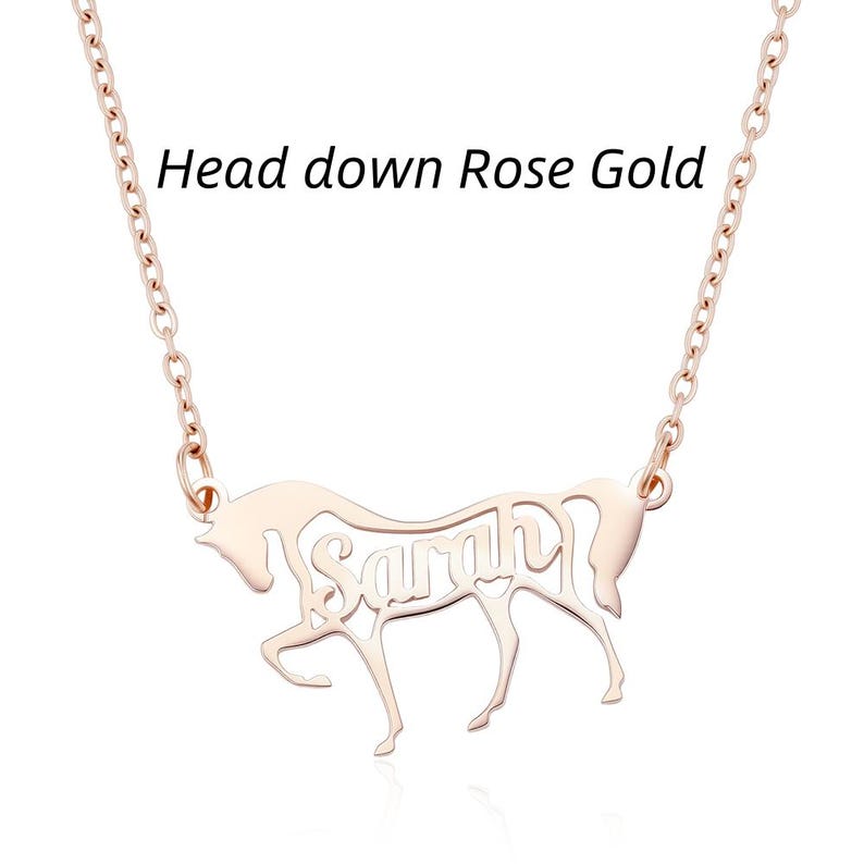 May include: A rose gold necklace featuring a pendant shaped like a horse with its head down. The name Sarah is cut out from the center of the horse's body. The text Head down Rose Gold is visible above the pendant on the plain white background.