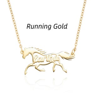 May include: A gold-toned necklace featuring a pendant shaped like a running horse with the name Eartha integrated into its body. The text Running Gold is positioned above the horse pendant, which is attached to a delicate gold-toned chain.
