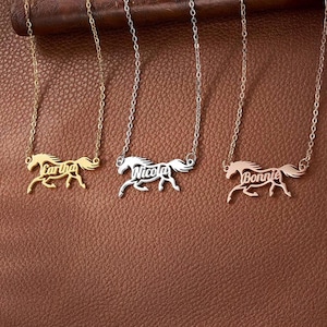 May include: Three necklaces with thin metal chains, each featuring a pendant shaped like a running horse. The horse pendants incorporate the names Cartha, Nicola, and Bonnie into their silhouettes. The set includes gold, silver, and rose gold tones.