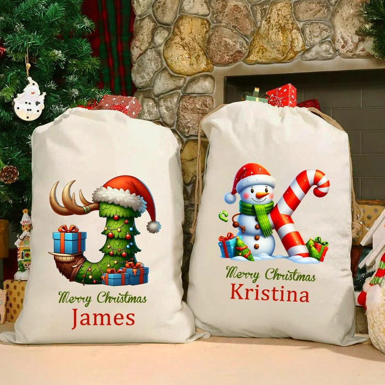 May include: Two white Christmas gift sacks. One sack features a Christmas tree design with a Santa hat and the name "James". The other sack has a snowman design with a candy cane and the name "Kristina". Both sacks have the text "Merry Christmas".
