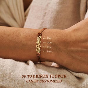 Puede incluir: Una pulsera dorada con diseños florales y un cordón marrón. La pulsera tiene el texto "Dec., Jun., Otc., Nov." y el texto "UP TO 8 BIRTH FLOWER CAN BE CUSTOMIZED".