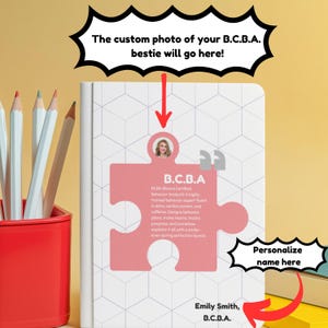 May include: A white notebook with a pink puzzle piece design featuring the text "B.C.B.A." and a photo placeholder. The notebook also includes the text "The custom photo of your B.C.B.A. bestie will go here!" and "Personalize name here."