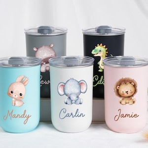 May include: A collection of five stainless steel tumblers with clear lids. Each tumbler features a different watercolor animal illustration: a bunny, hippo, elephant, dinosaur, and lion. Names are printed below each animal in a script font.